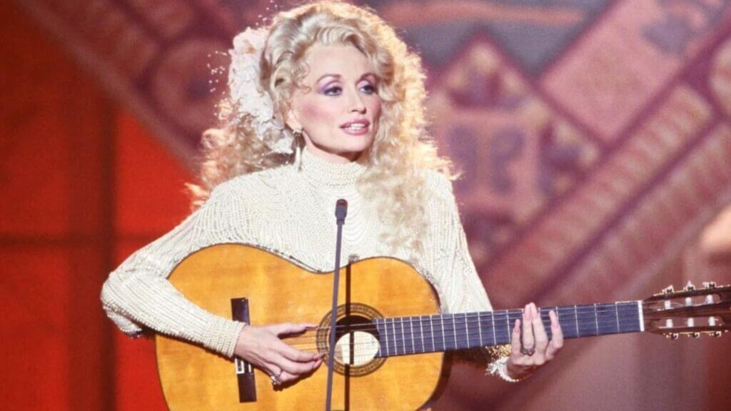 Country music star and 2023 ACM Award host Dolly Parton playing a Guitar