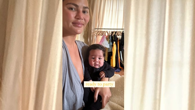 Chrissy Teigen holding her son while displaying her amazing wardrobe in Italy