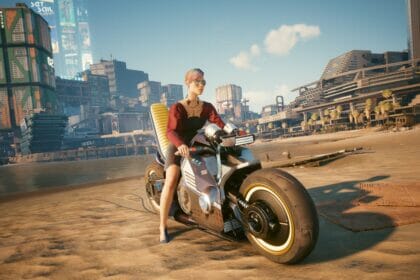 V sits on her motorcycle on the beach in Cyberpunk 2077