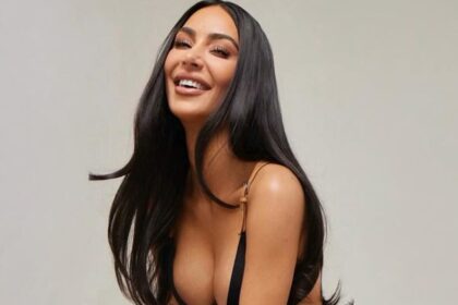 Kim Kardashian posing in black bikini top and skirt.