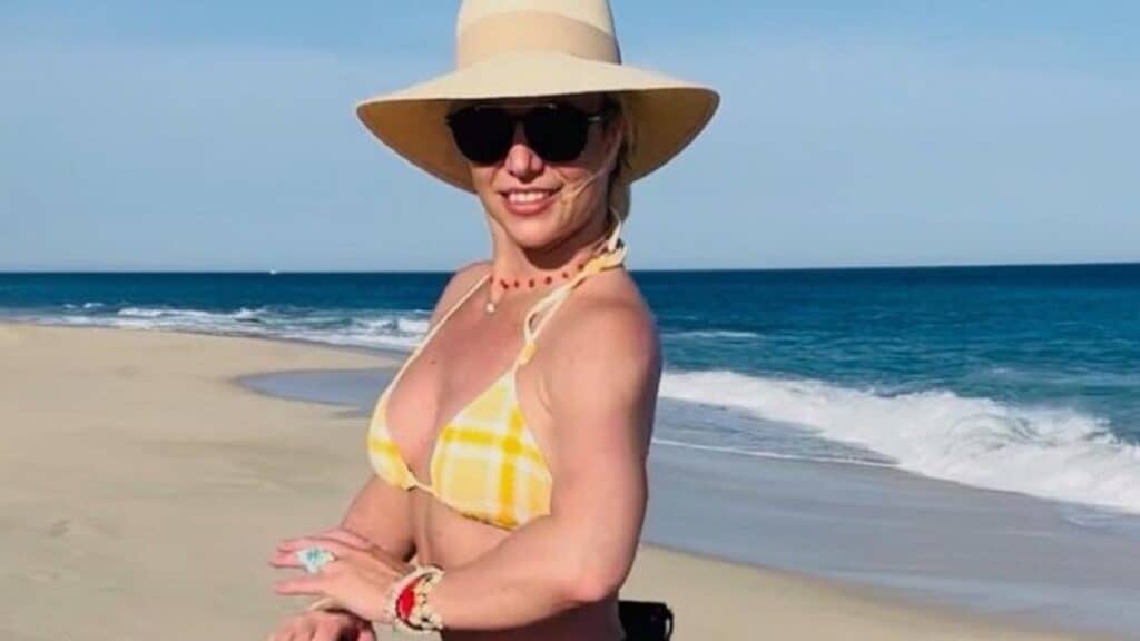 Britney spears wears a hat and sunglasses on the beach.