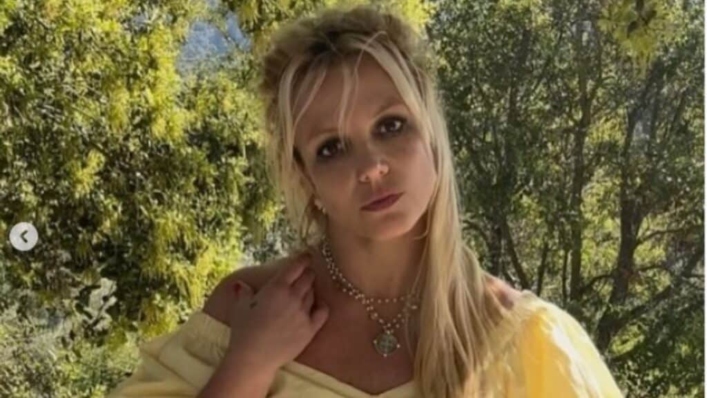 Britney Spears wearing a yellow top and posing for a photo.