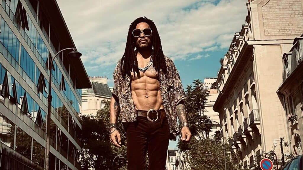 Lenny Kravitz unbuttons his shirt while outdoors