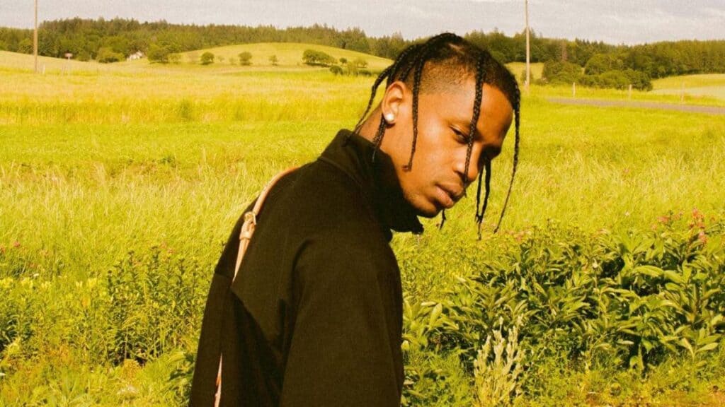 Travis Scott, in a black outfit, turns his back to the camera