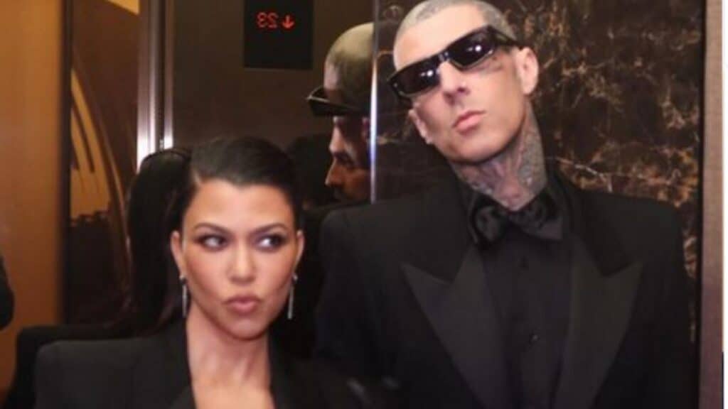 Kourtney Kardashian and Travis Barker, dressed in black and posing together.